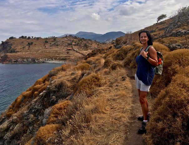 woman-dressed-in-shorts-and-blue-top-walking-a-trekking-path-along-the-dry-grassy-coastal-cliffs-of_t20_9lYjYA